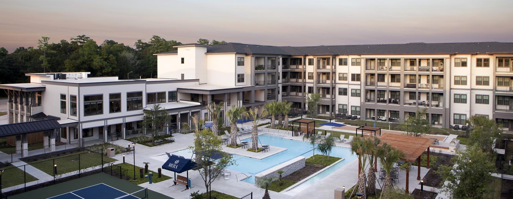 a building with a pool and trees in the front