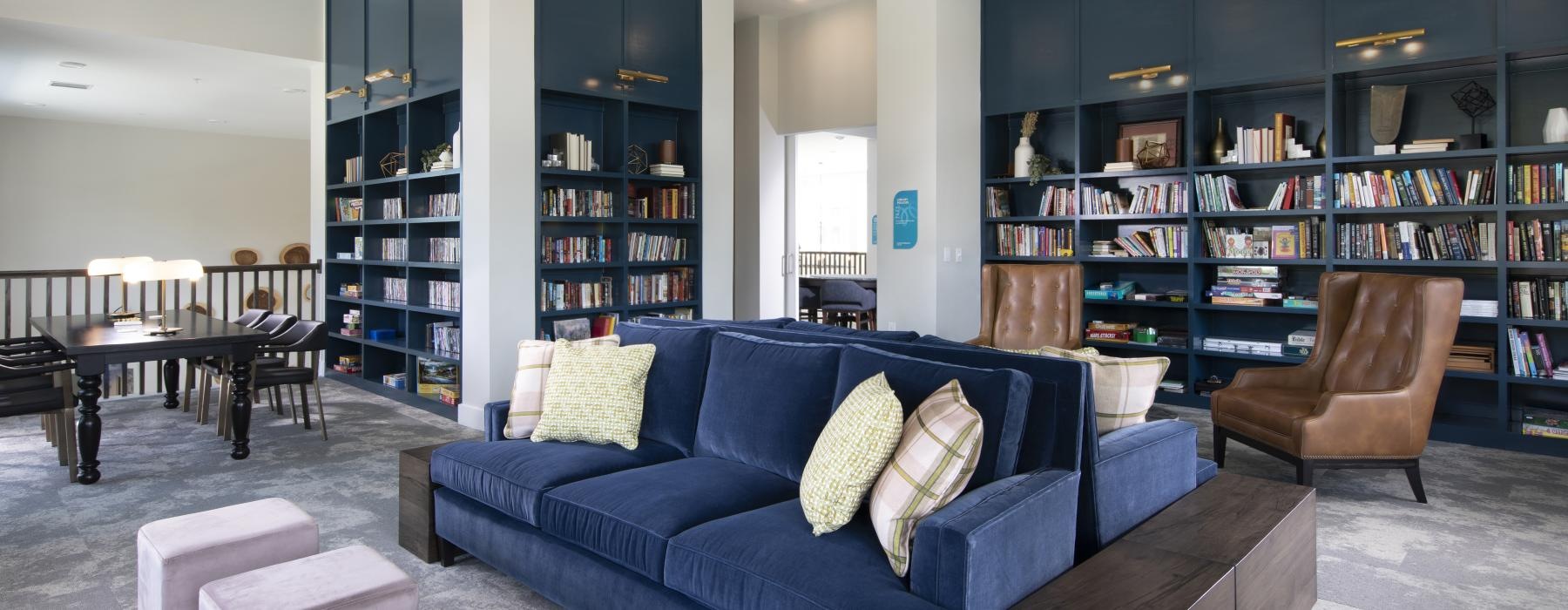 a clubhouse room with a blue couch and bookshelves